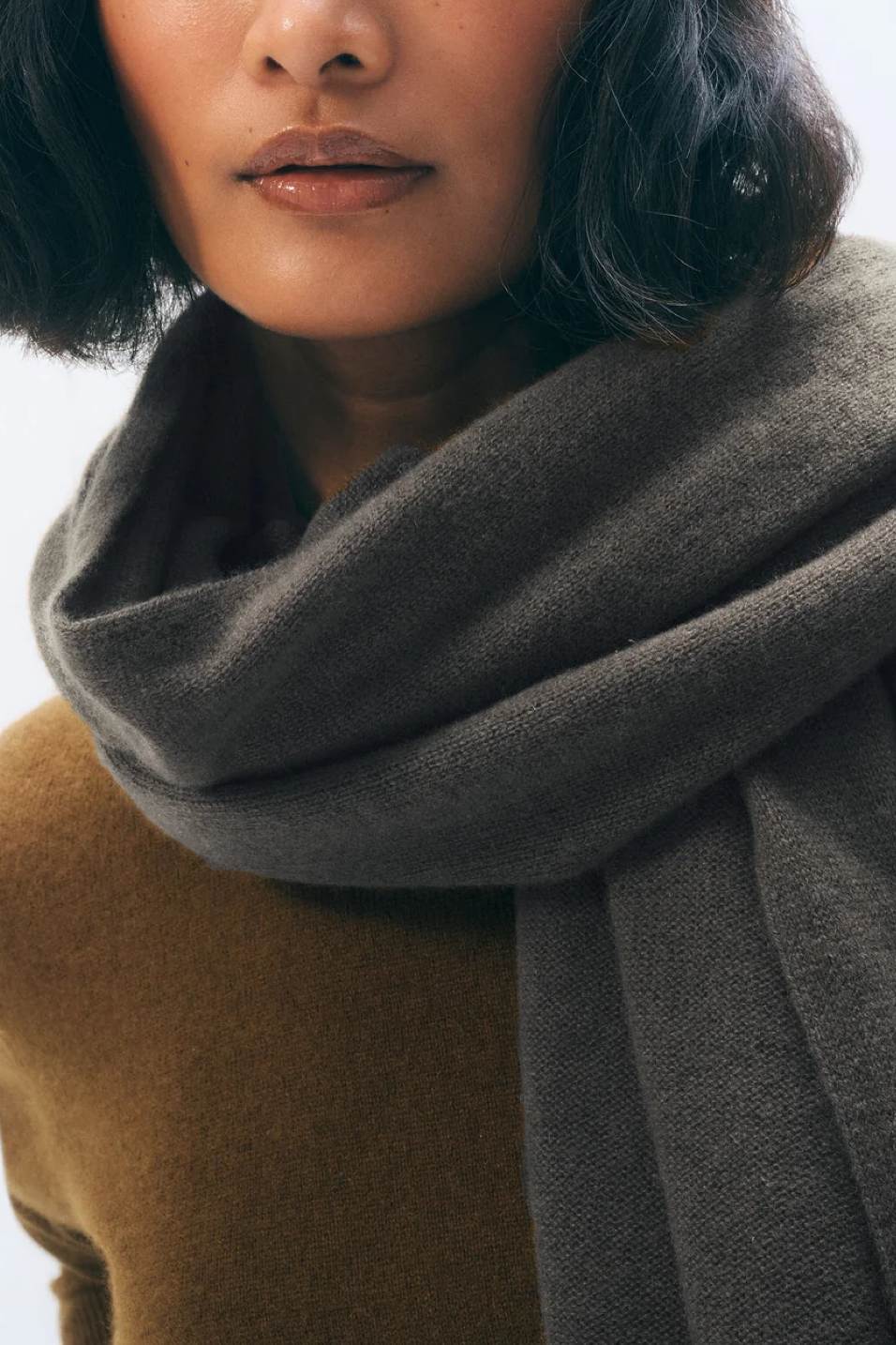 Close-up of a person wearing a dark brown scarf with a blurred background