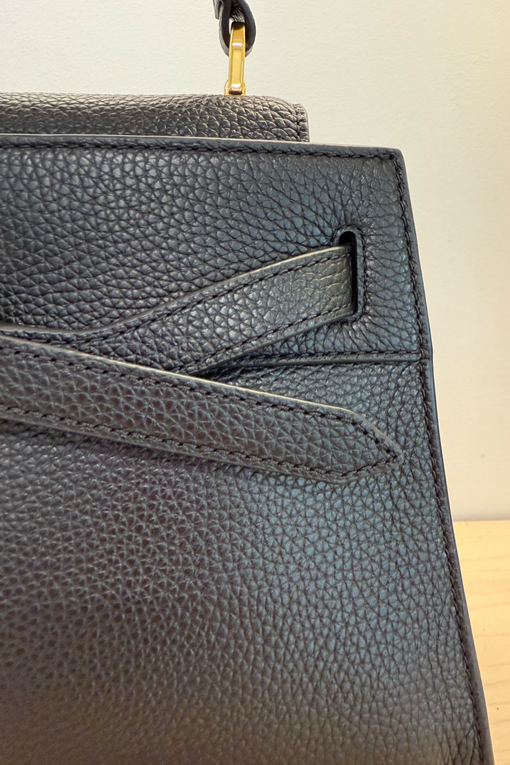 Close-up of a black pebbled leather top handle bag.
