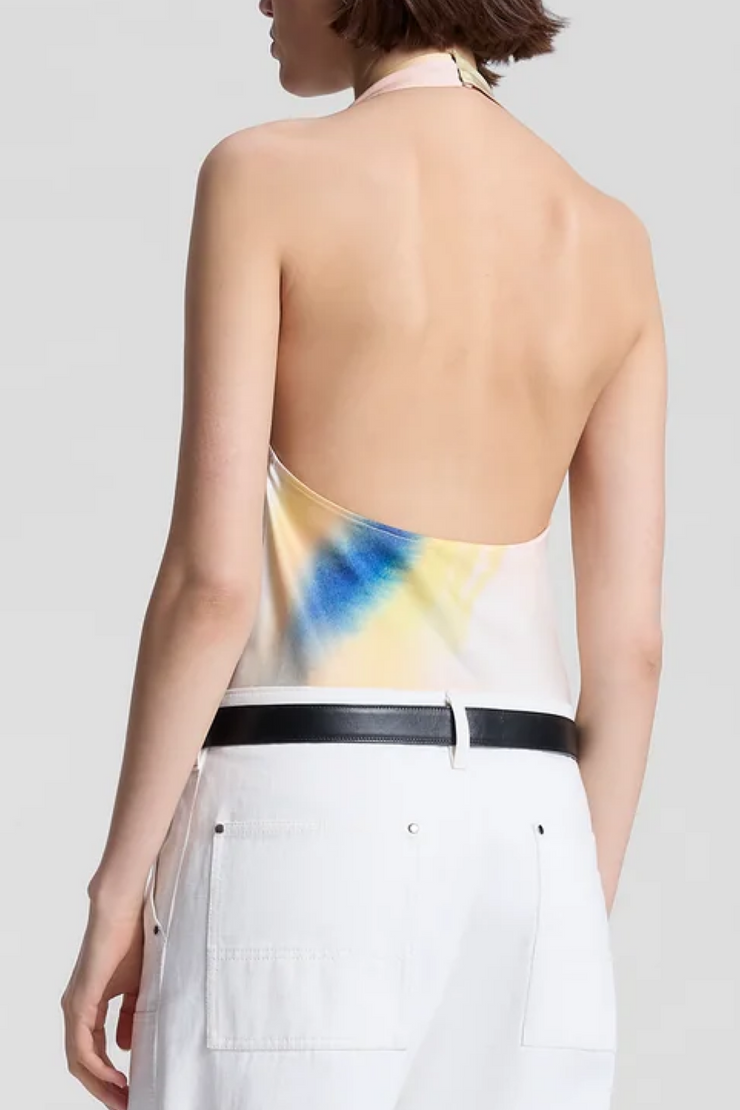 Woman wearing a tie-dye halter top with a plain background