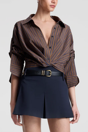 Woman wearing a brown striped shirt and navy shorts on a white background