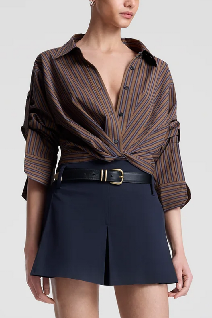 Woman wearing a brown striped shirt and navy shorts on a white background
