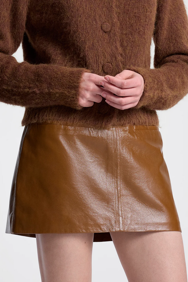 Brown sweater and leather skirt worn by a person on a white background