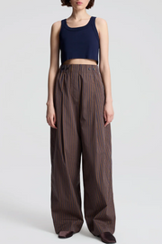 Person wearing a navy crop top and brown striped pants on a white background
