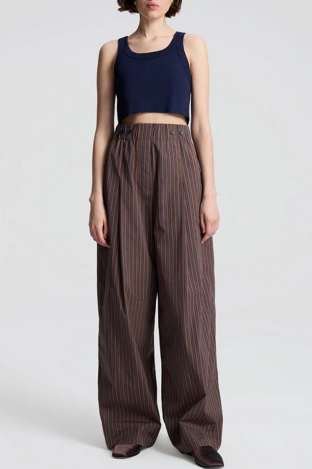 Person wearing a navy crop top and brown striped pants on a white background