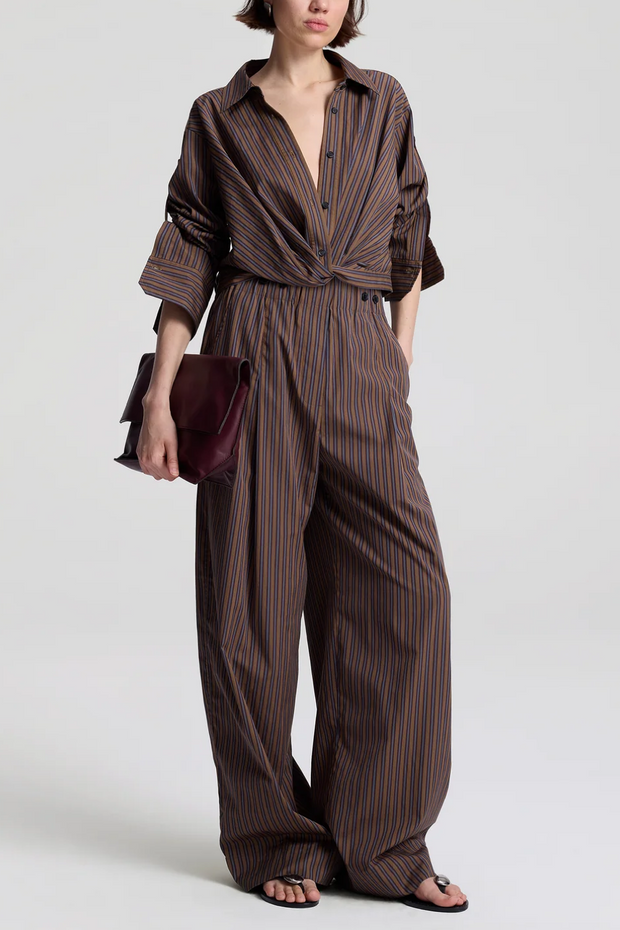 Person wearing a brown striped outfit holding a matching clutch against a white background