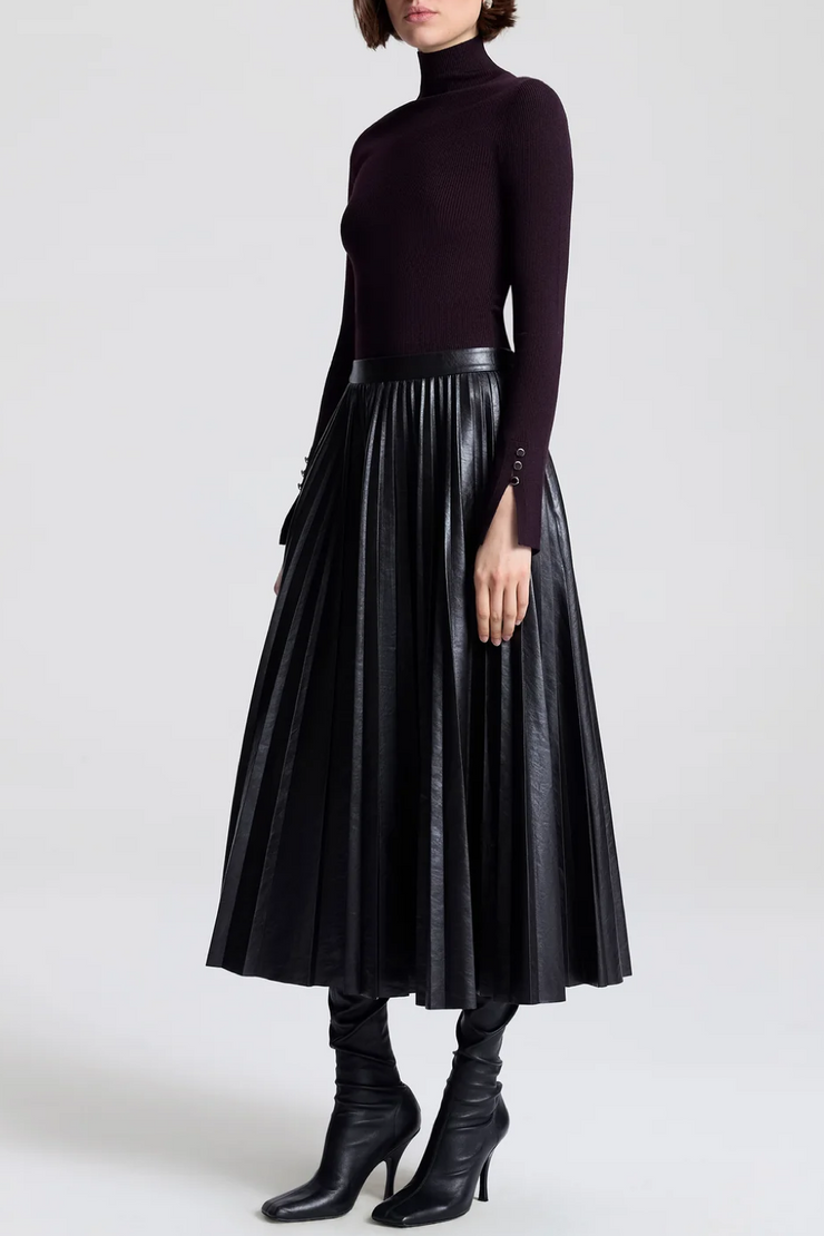 Side image of model wearing a vegan pleated leather skirt in deepest brown