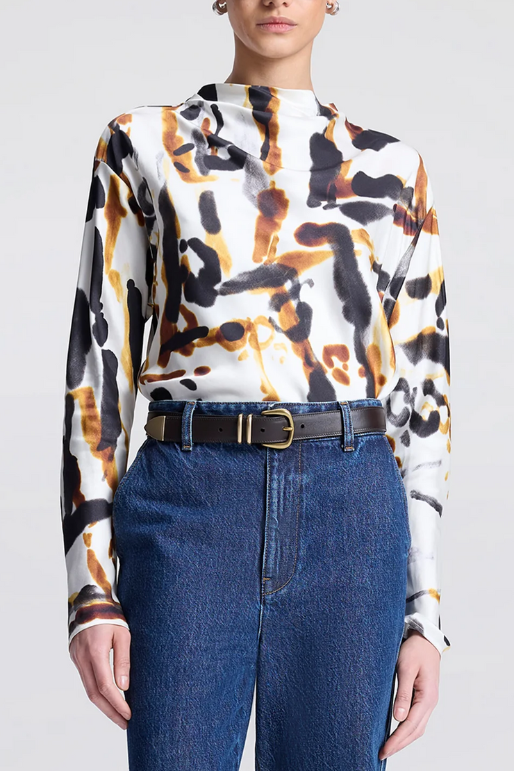 Person wearing a patterned blouse and blue jeans on a plain background