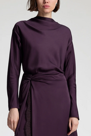 Purple long-sleeve top with a tie waist skirt on a white background