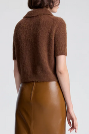 Brown knitted top worn by a person on a white background