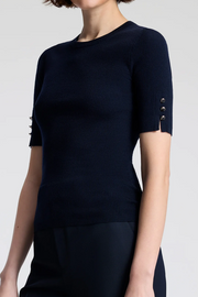 Navy knit top with decorative buttons on sleeves against a white background