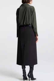 Person wearing a long green shirt and black skirt on a white background