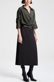 Person wearing a green shirt, black skirt, and black boots on a white background