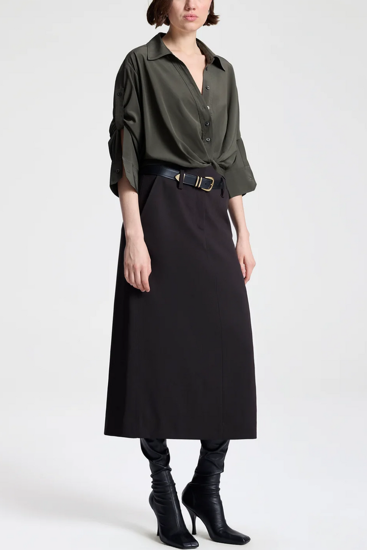 Person wearing a green shirt, black skirt, and black boots on a white background