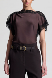 Brown blouse with black lace details and black pants on a white background