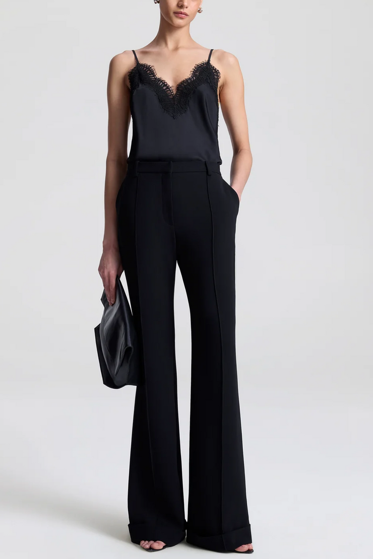 Woman wearing a black lace top and wide-leg pants on a white background