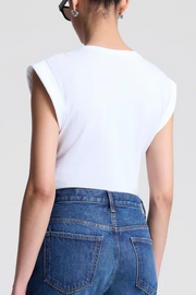 Person wearing a white sleeveless top and blue jeans on a plain background