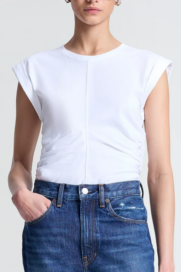 Person wearing a white sleeveless top and blue jeans on a plain background