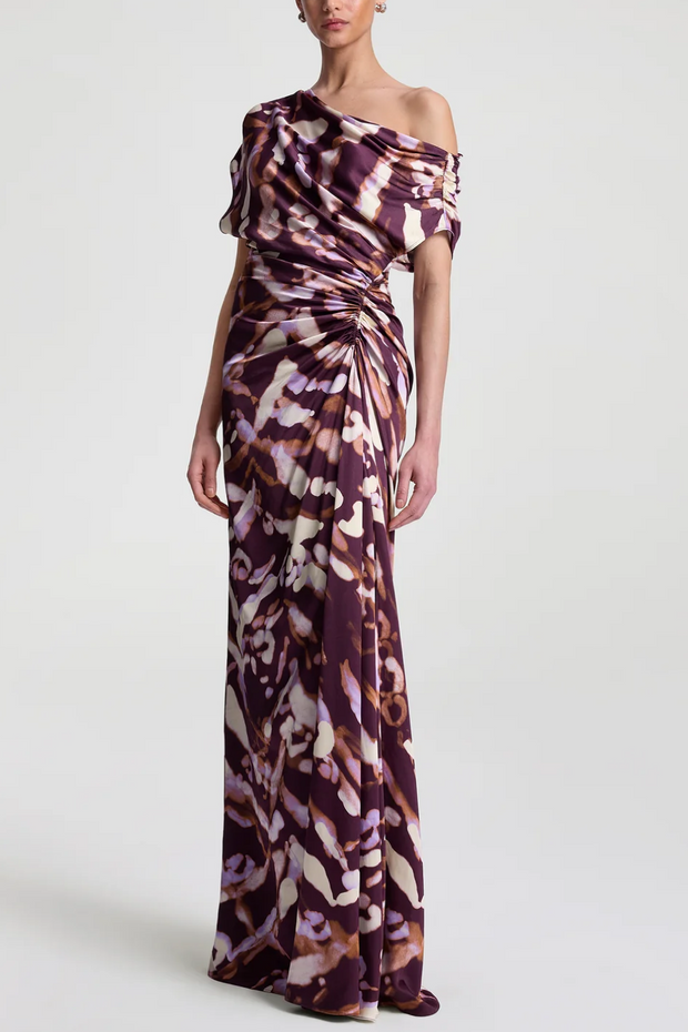 Woman wearing a one-shoulder patterned dress on a white background