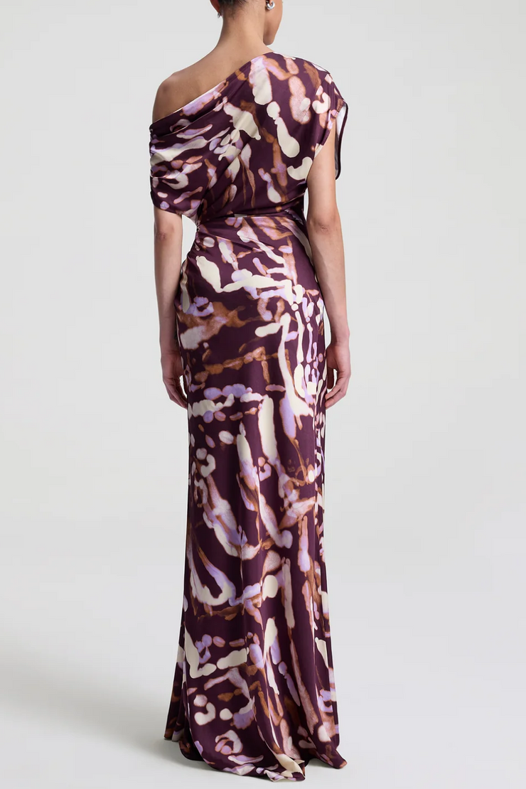 Woman wearing a one-shoulder patterned dress on a white background