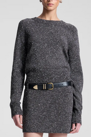 Person wearing a gray textured top/skirt with a black belt on a white background