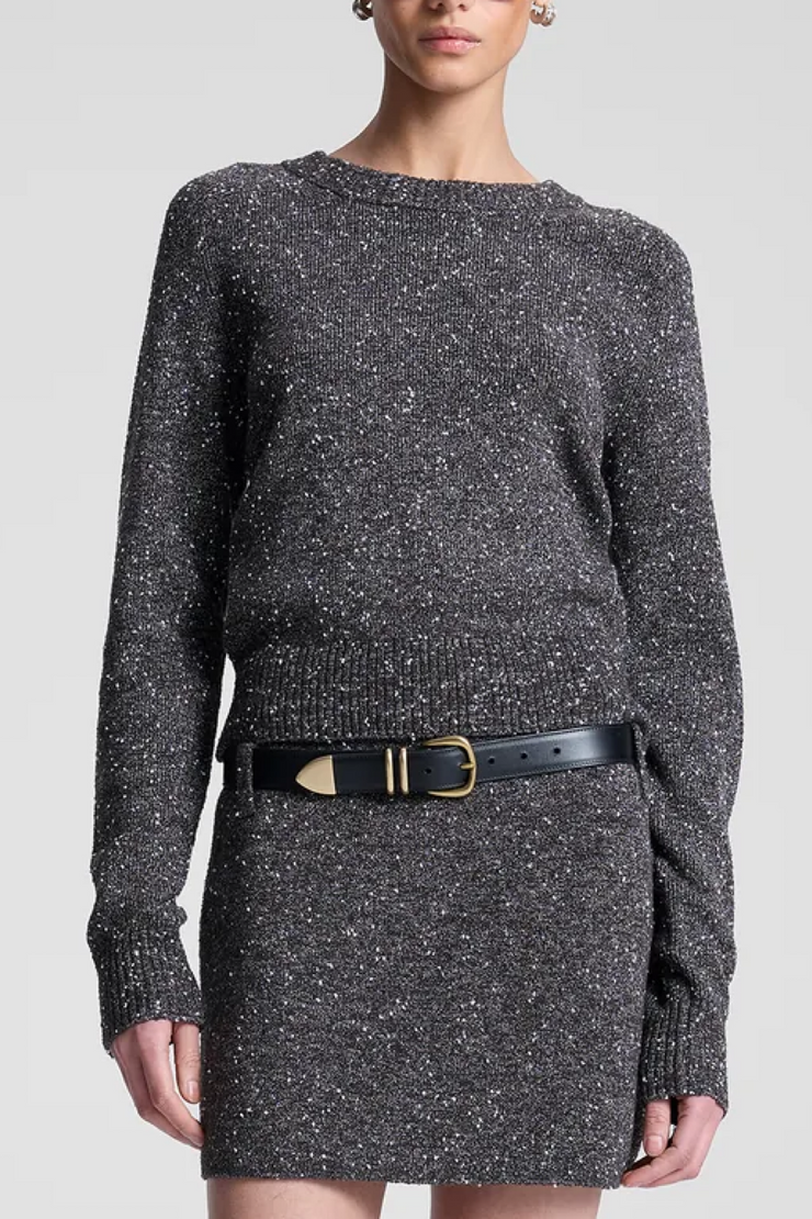 Person wearing a gray textured top/skirt with a black belt on a white background