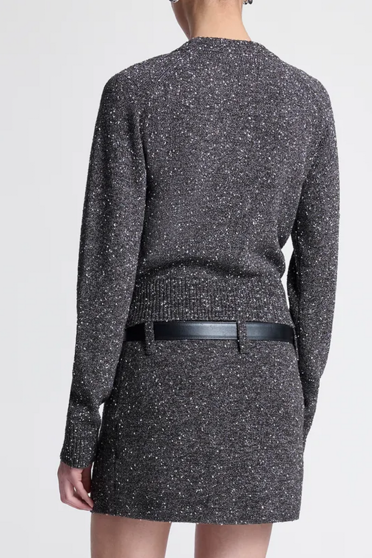 Back view of a person wearing a textured top/skirt with a belt on a white background