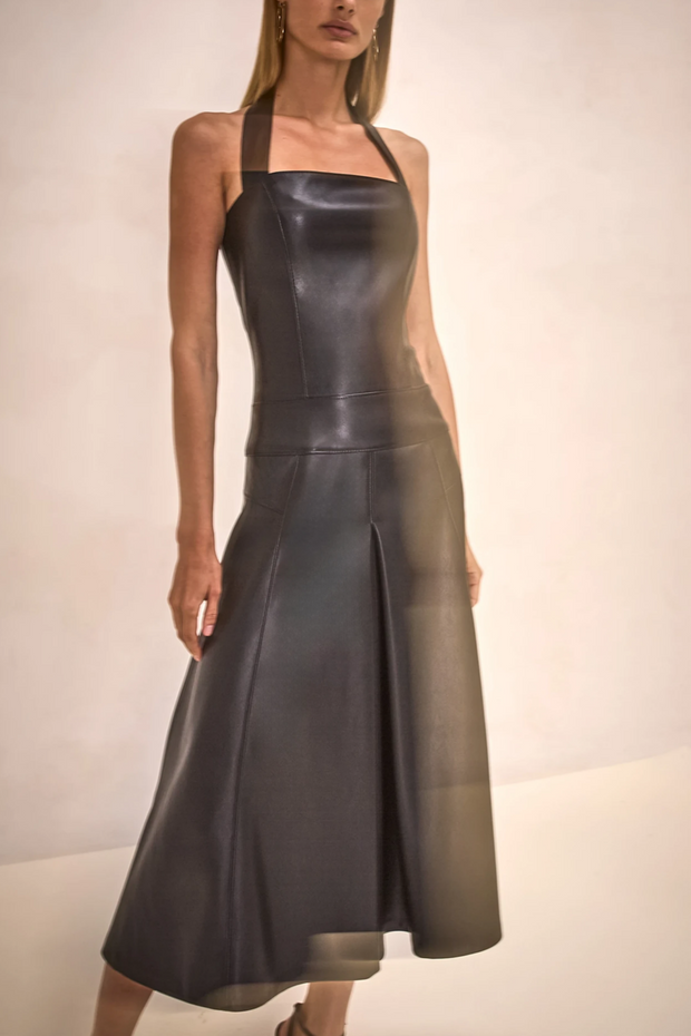 Woman wearing a black leather dress against a neutral background