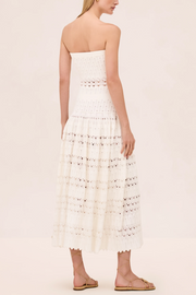 Woman wearing a strapless white lace dress on a beige background