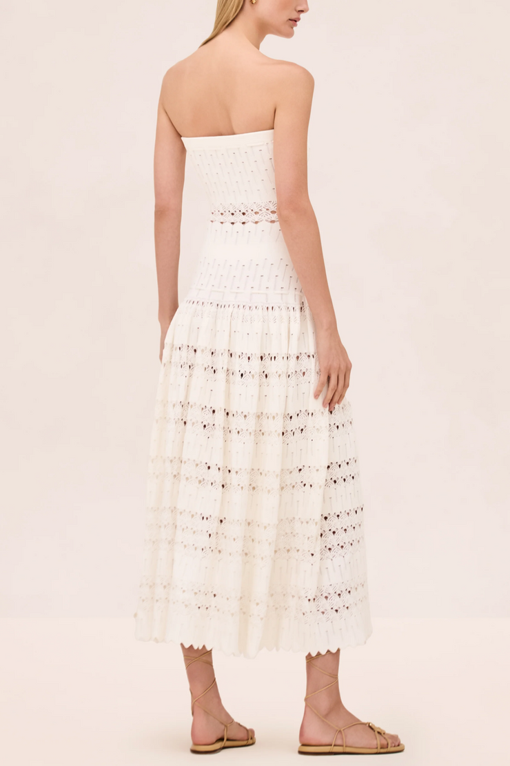 Woman wearing a strapless white lace dress on a beige background