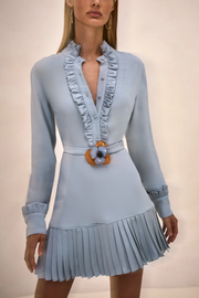 Light blue dress with ruffled collar and pleated skirt on a neutral background