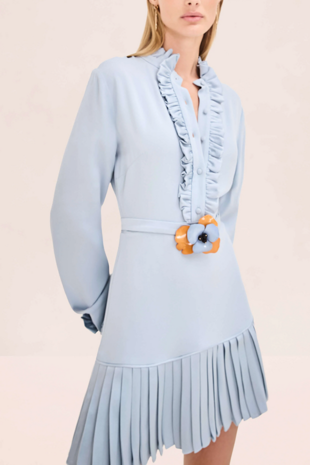 Light blue dress with ruffled details and a belt on a beige background