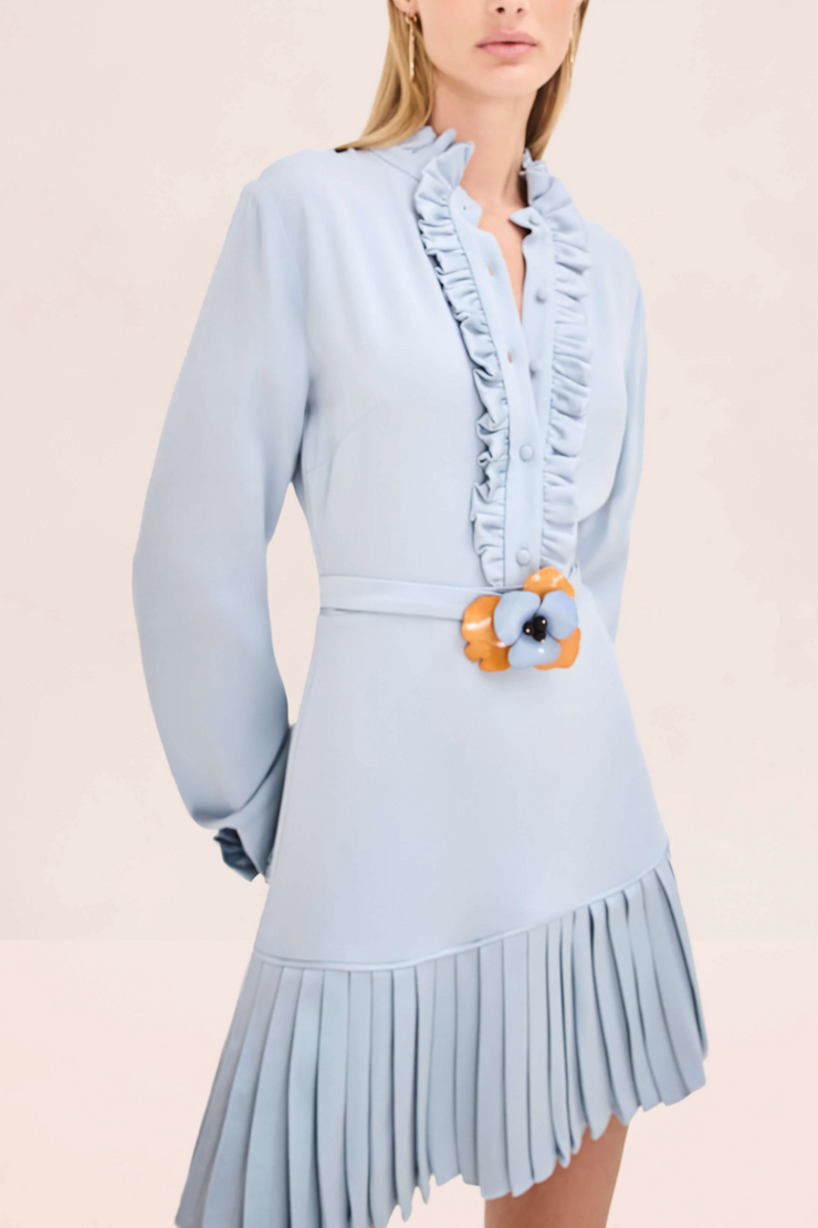 Light blue dress with ruffled details and a belt on a beige background