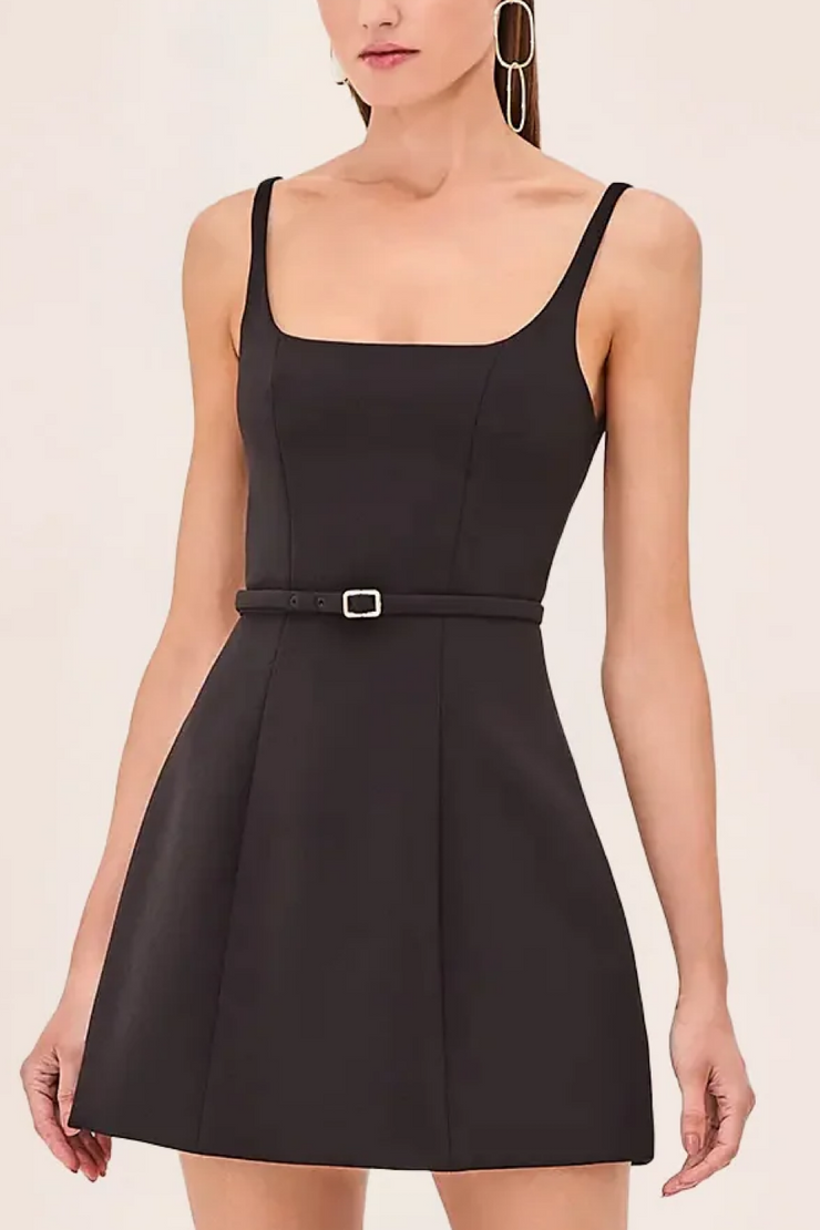 Black dress with a belt worn by a model on a light pink background