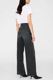 Person wearing black wide-leg jeans and a white top on a white background