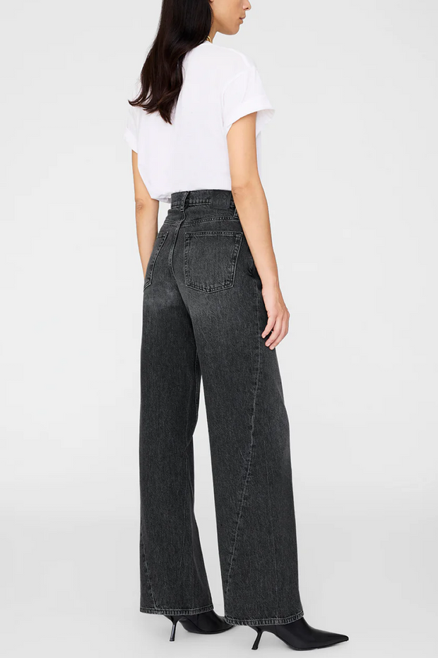 Person wearing black wide-leg jeans and a white top on a white background