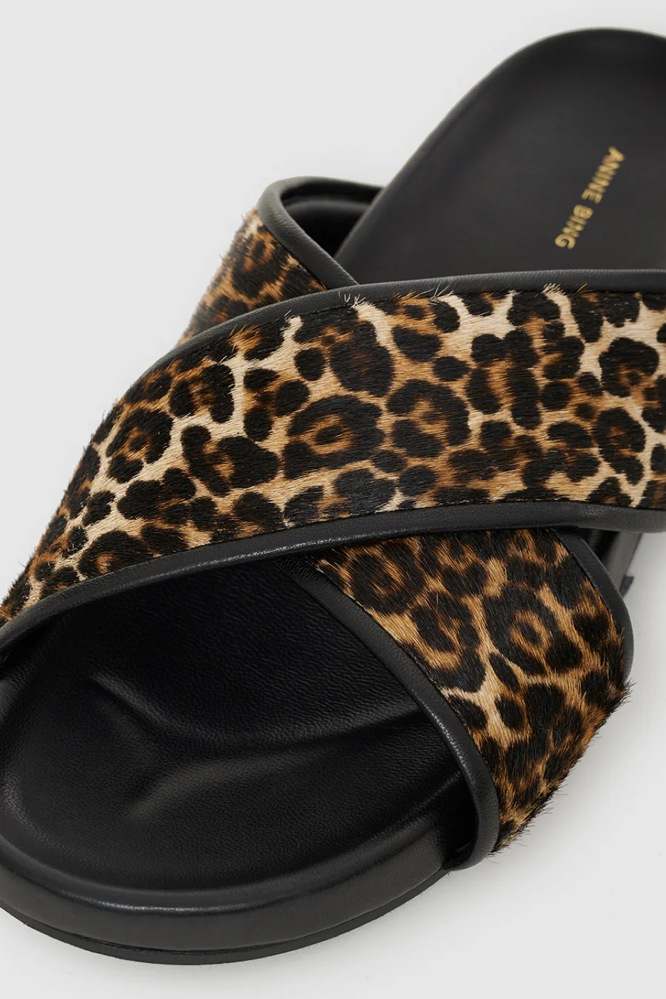 Leopard print slide sandal with black sole on a light gray background