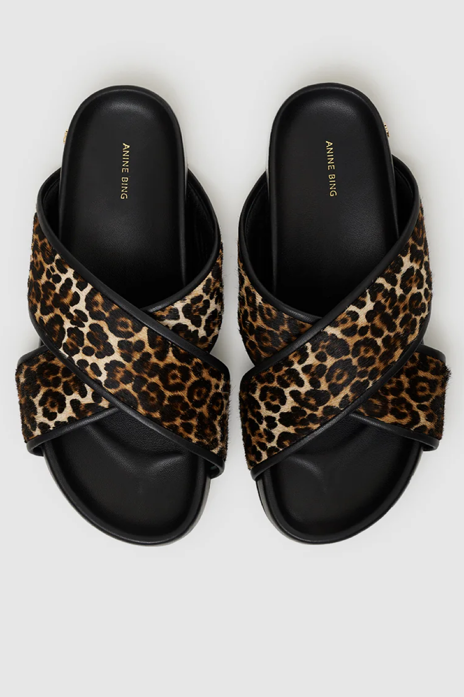 Pair of leopard print sandals with black straps on a white background