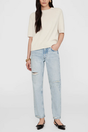 Person wearing a cream sweater and light blue jeans on a white background