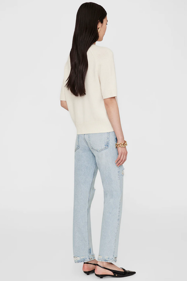 Person wearing a cream top and light blue jeans on a white background