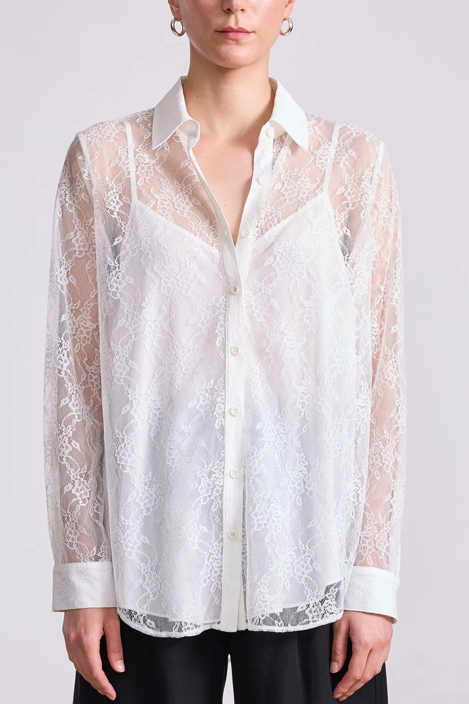 White lace shirt worn by a person on a plain background