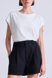 Person wearing a white top and black shorts on a light gray background