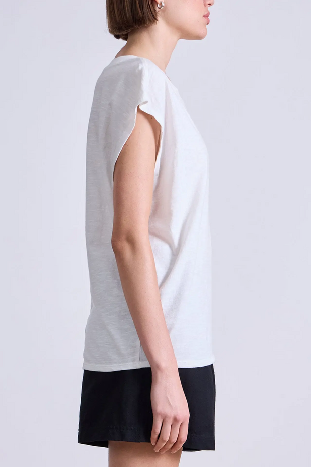 Woman wearing a white sleeveless top and black skirt on a light gray background
