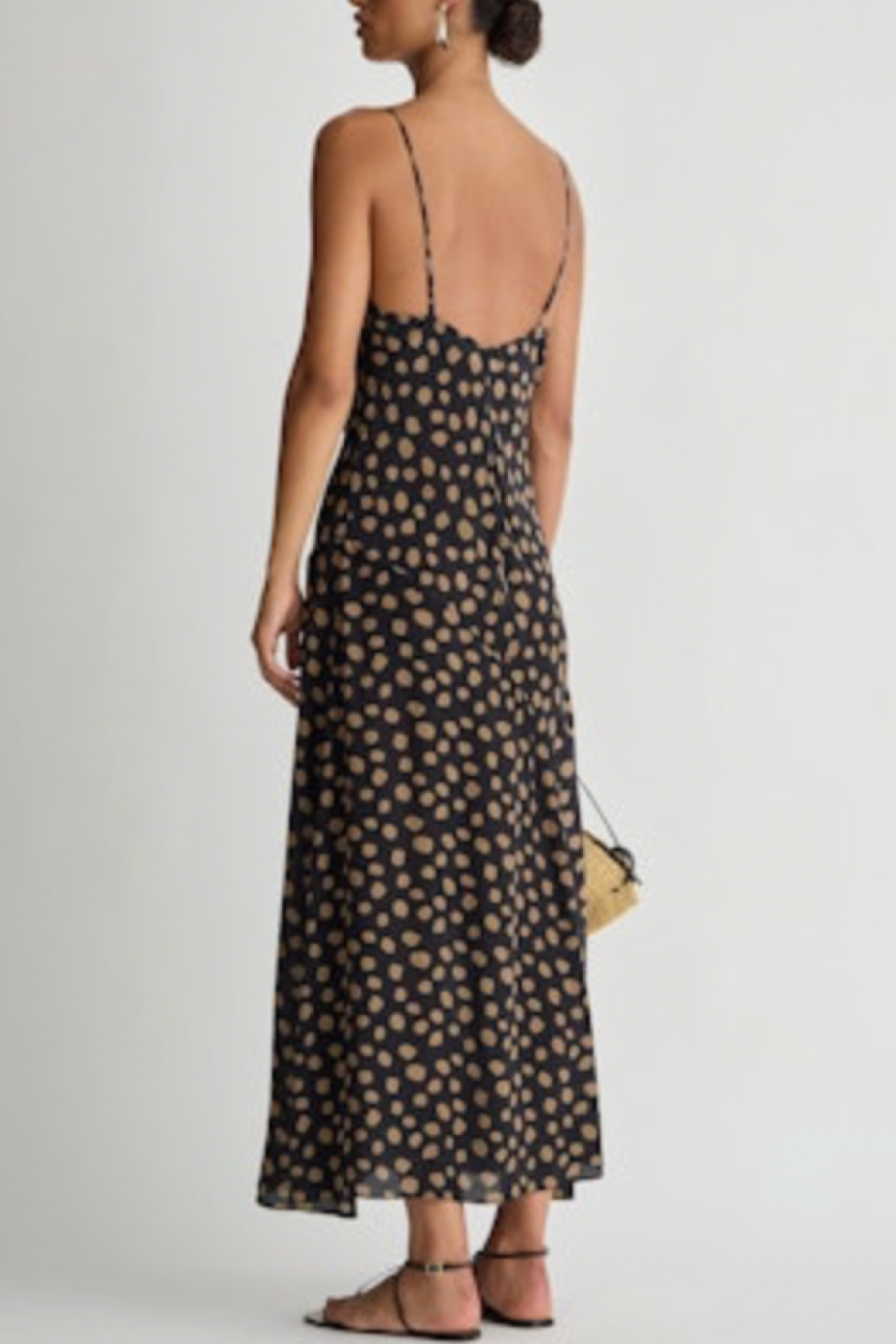 Woman wearing a black dot dress on a plain background