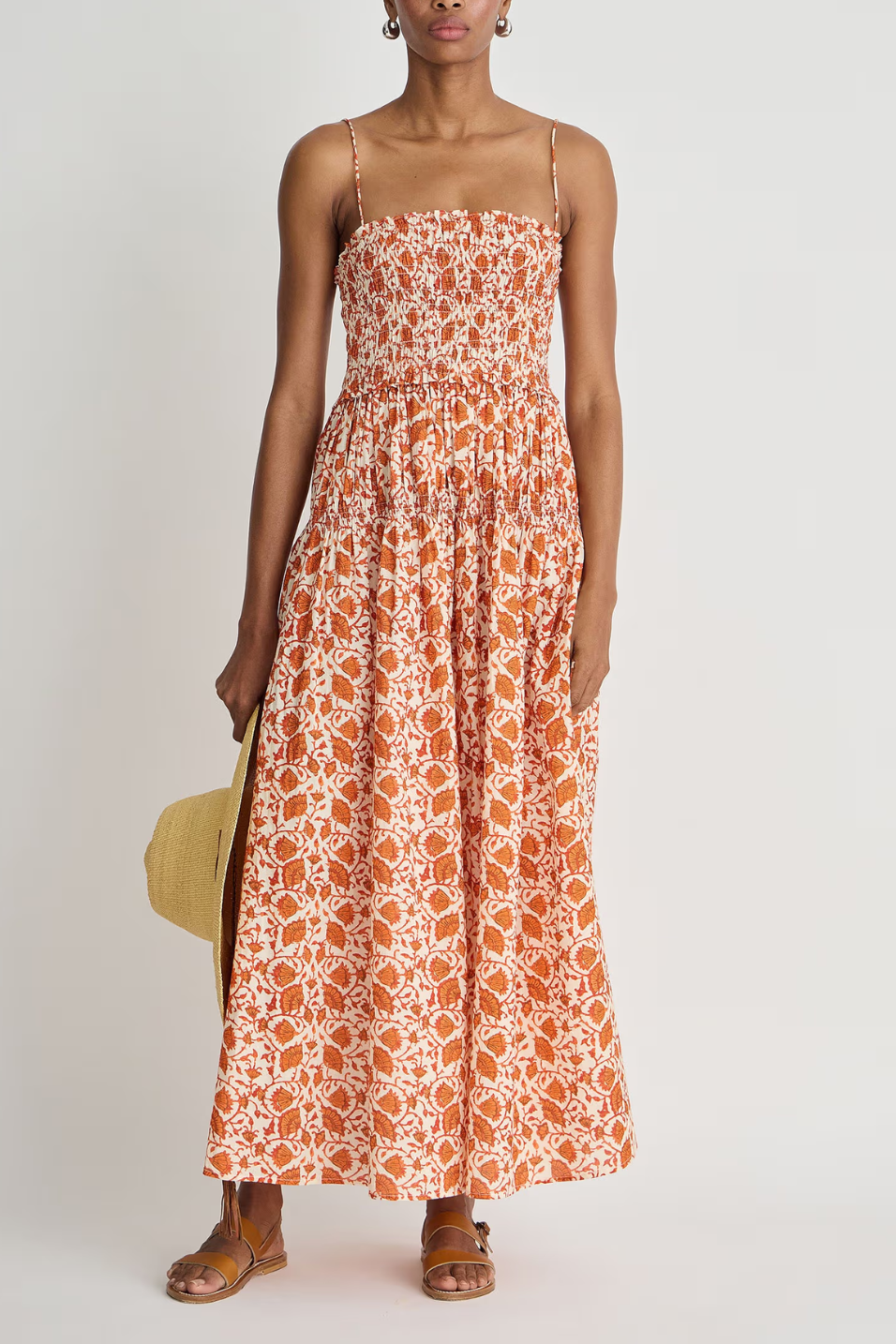 Woman wearing an orange floral dress against a white background