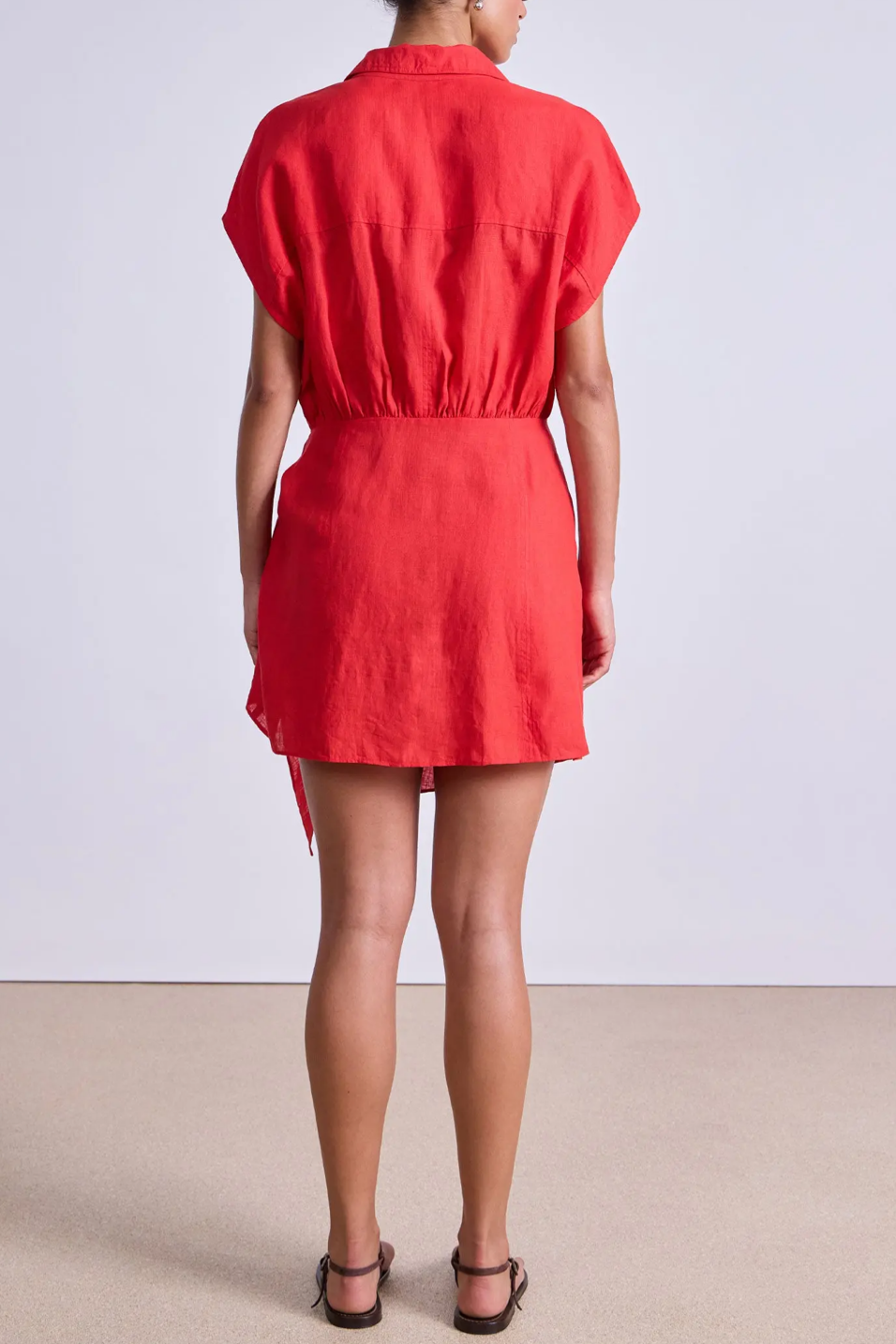Person wearing a red dress against a plain background