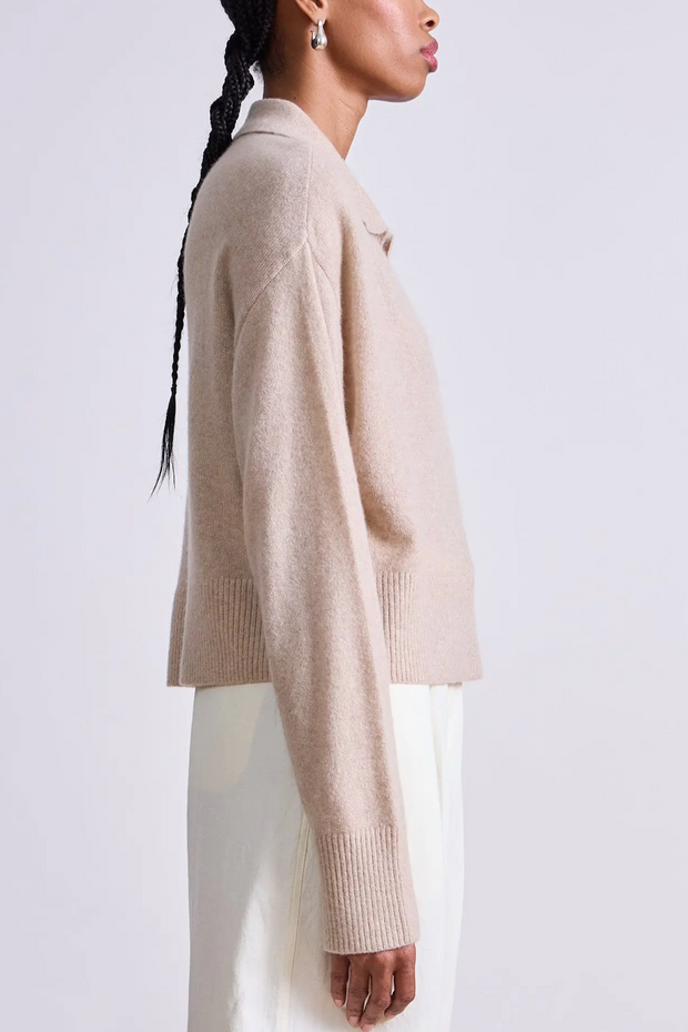 Person wearing a beige sweater against a white background