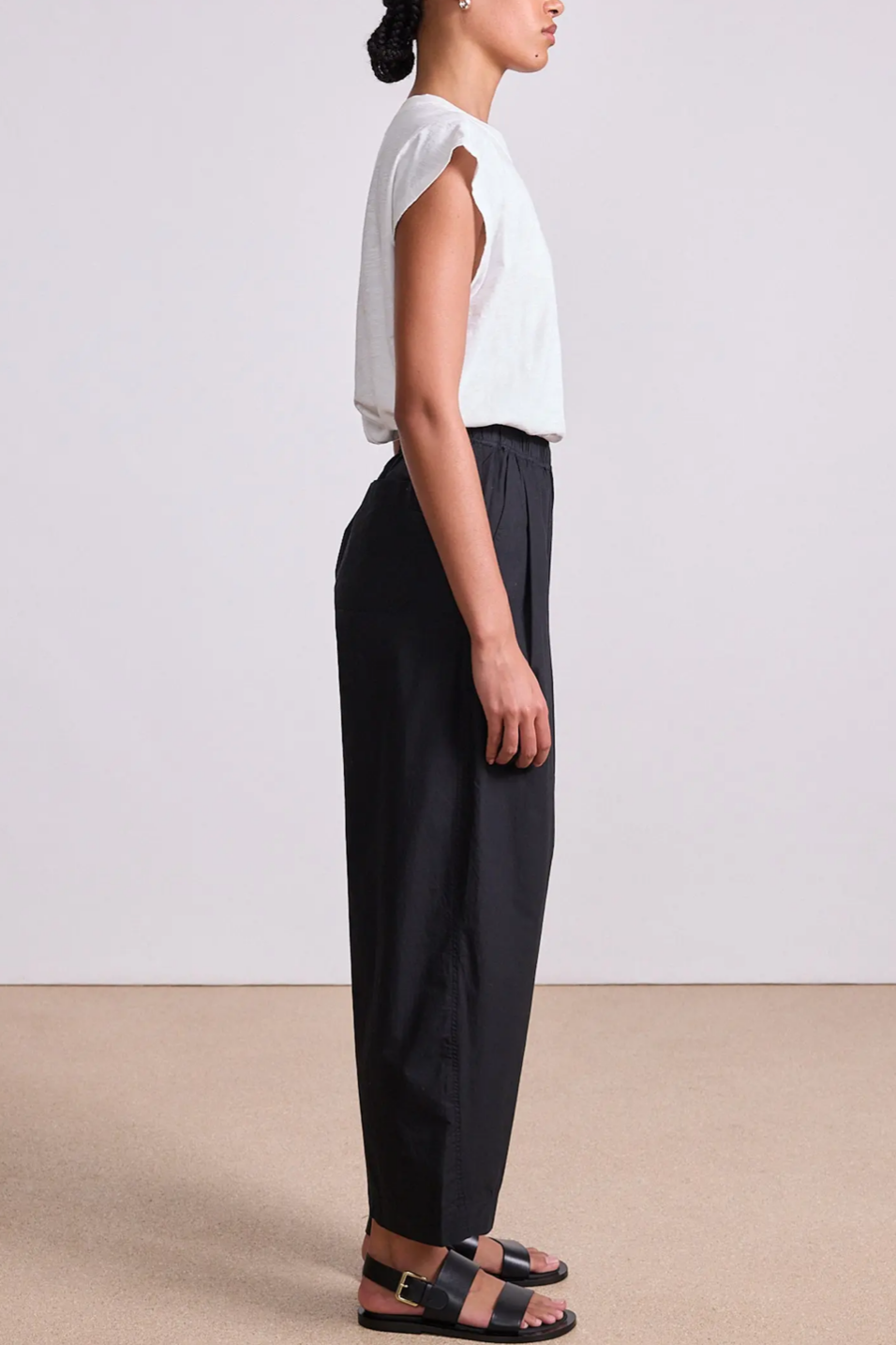 Person wearing a white top and black pants on a plain background