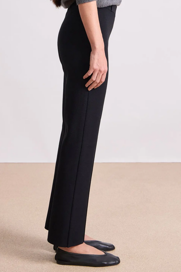 Person wearing black pants on a plain background