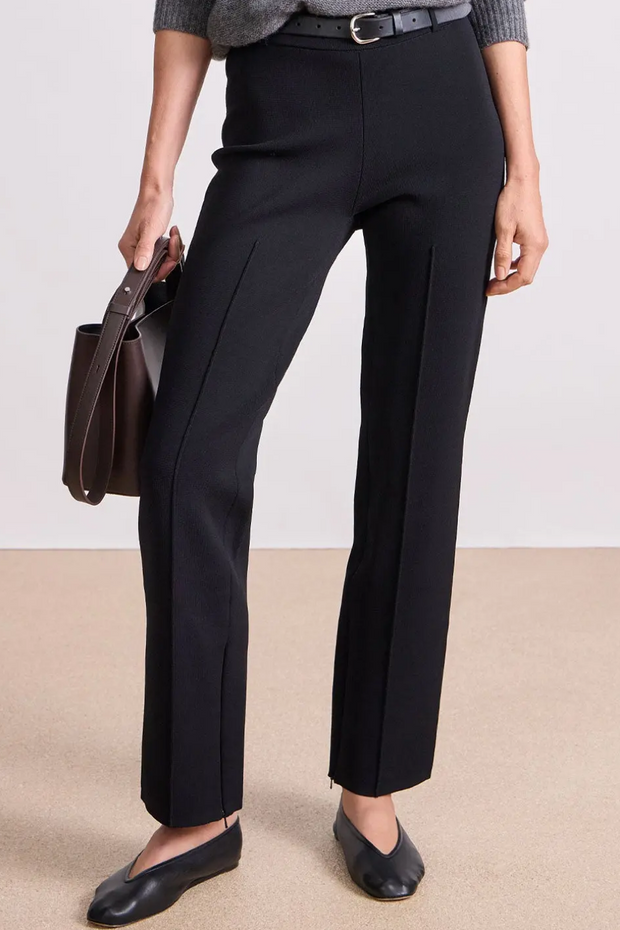 Person wearing black pants with a plain background