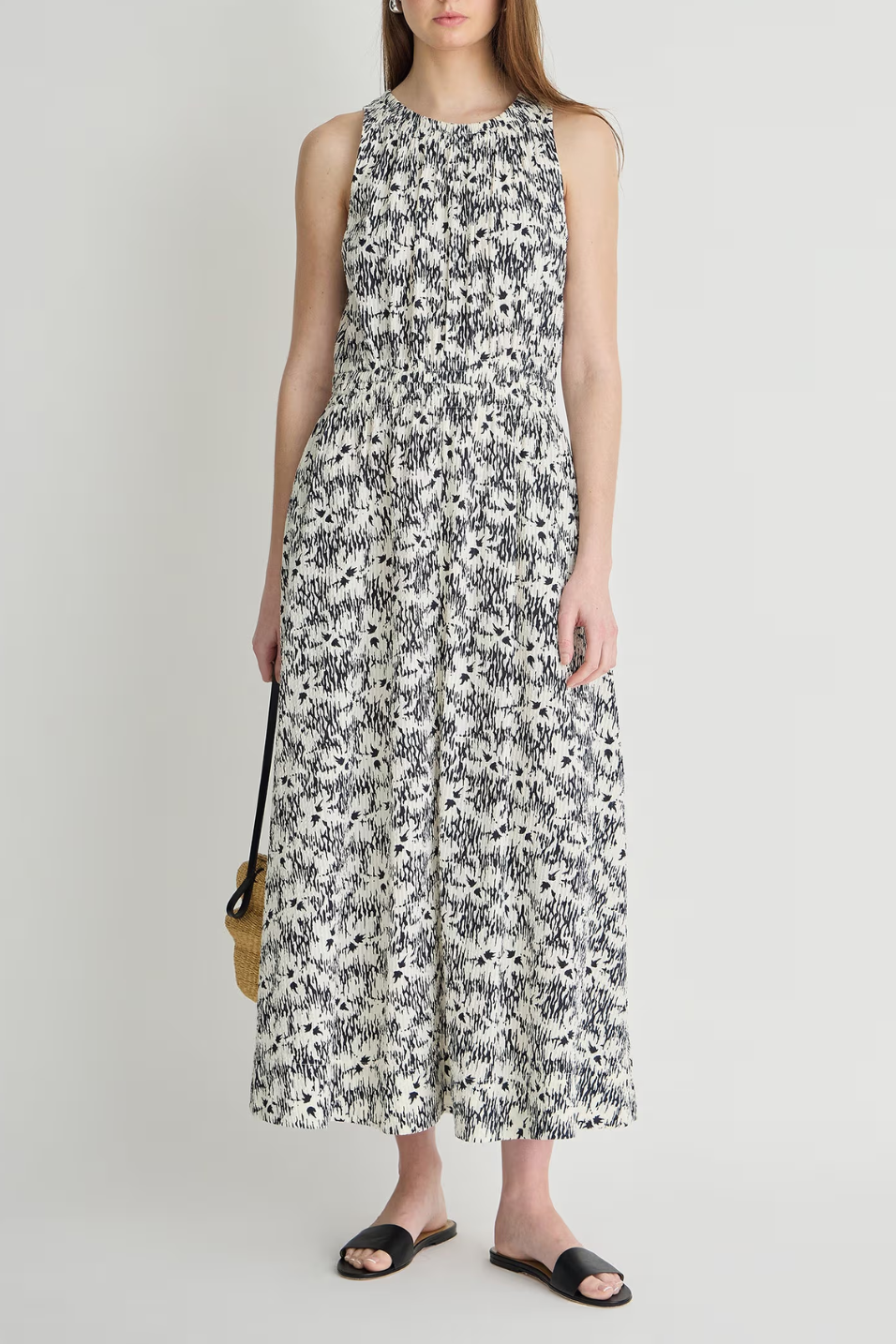 Woman wearing a sleeveless floral dress against a plain background
